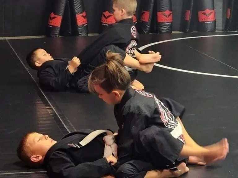 Young students practicing ground control and positioning during a kids' brazilian jiu jitsu session.