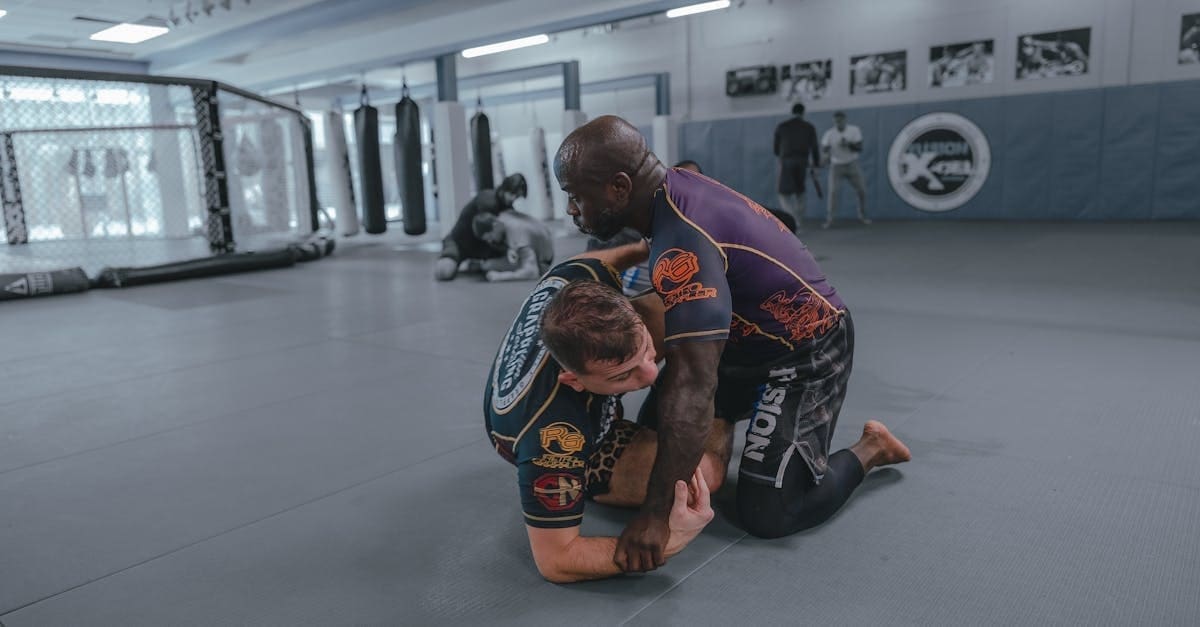 An instructor and a teenage student demonstrating a Kimura shoulder lock, emphasizing the importance of safety and BJJ mat etiquette for teens in a martial arts academy.