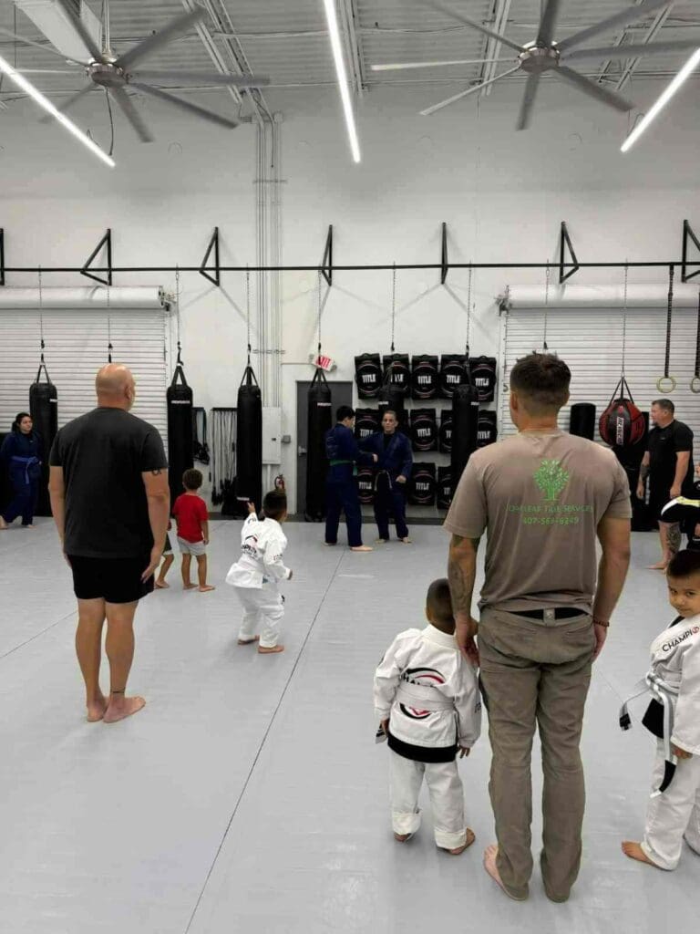 Young Brazilian Jiu-Jitsu student practicing a ground control technique with an adult training partner while learning martial arts training fundamentals.